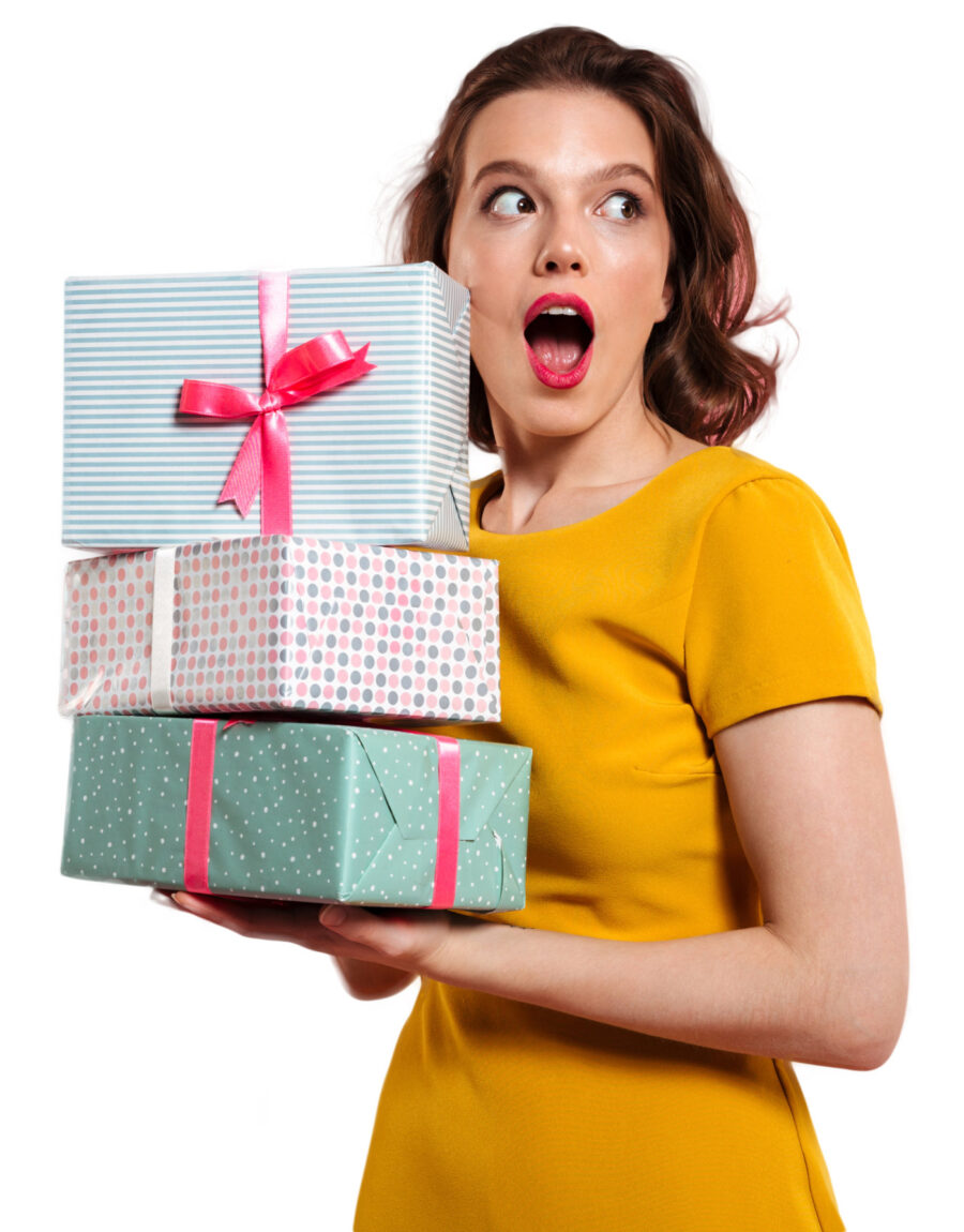 Close-up portrait of shocked pretty girl with bright makeup holding heap of presents, looking aside, isolated on pink background